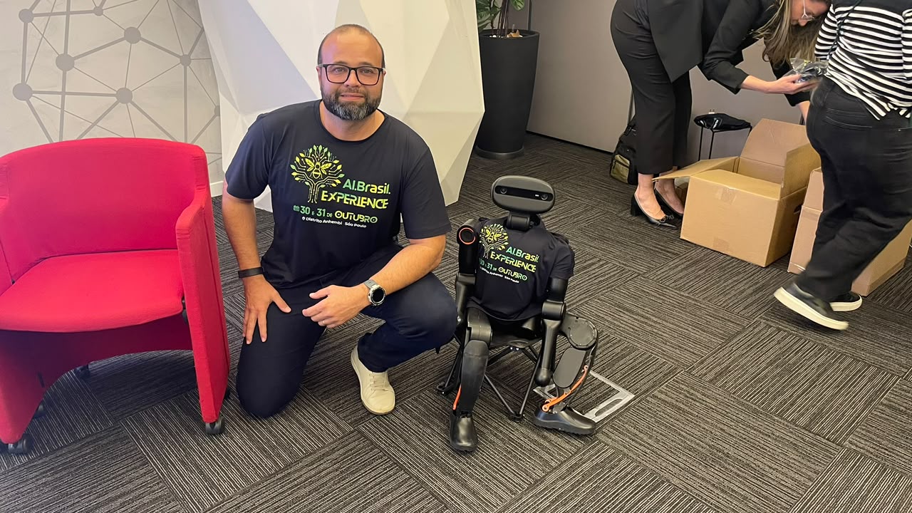 Robô humanoide vestindo a camiseta do AI Brasil Experience ao lado de organizador